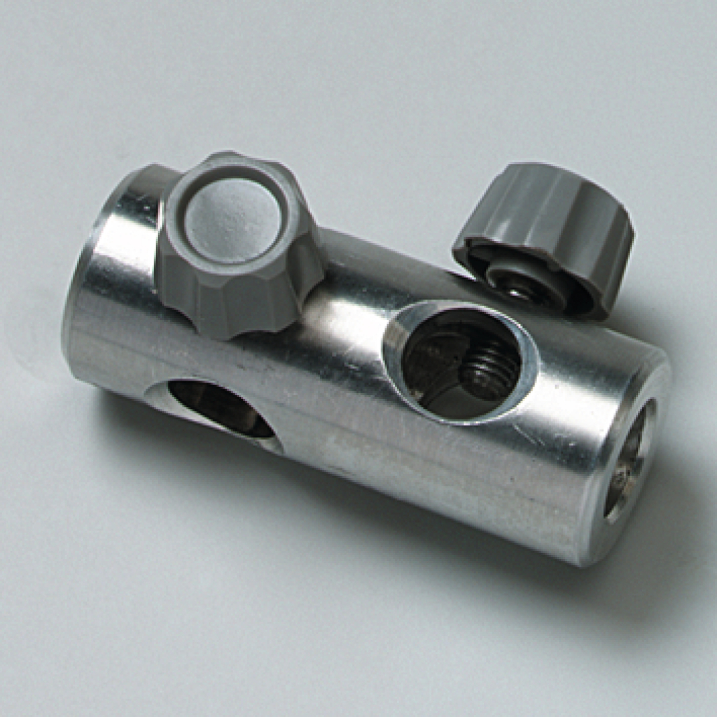 Das Bild zeigt ein metallisches Verbindungselement mit zwei grauen Stellknöpfen und mehreren Öffnungen. Es könnte Teil einer experimentellen Apparatur im Bildungsbereich sein, wahrscheinlich zur Regulierung von Flüssigkeiten oder Gasen.