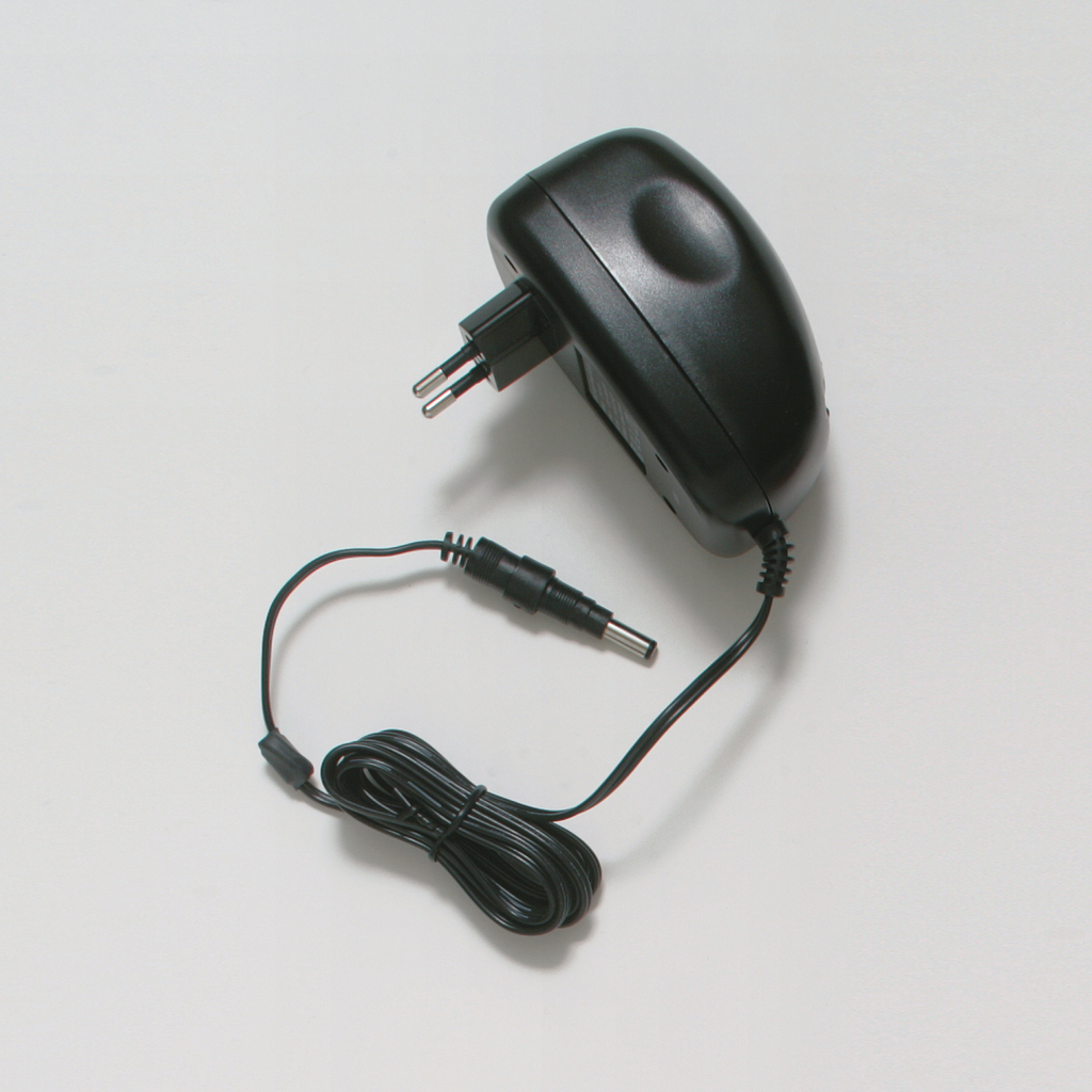 Das Bild zeigt ein schwarzes Netzteil mit einem Eurostecker, das für die Stromversorgung elektrischer Geräte verwendet wird. Es hat ein abgehendes Kabel mit einem Rundstecker für den Anschluss an verschiedene Geräte oder Experimentierbedarf.