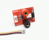 Das Bild zeigt eine rote elektronische Platine mit verschiedenen Bauteilen, darunter Anschlüsse und Widerstände, die für Experimente im Bildungsbereich verwendet werden können. Eine angeschlossene Kabelverbindung befindet sich im Vordergrund, die zur Steuerung dienen könnte.