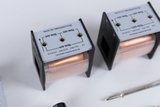 Das Bild zeigt zwei elektrische Spulen mit verschiedenen Wicklungen und technischen Angaben auf der Oberseite. Die Spulen sind für Experimentierzwecke im Bildungsbereich konzipiert und sind nicht für Netzspannung geeignet.