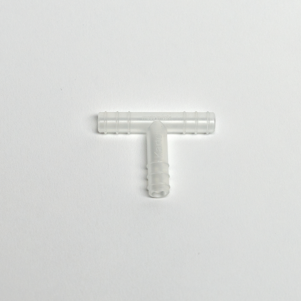 Das Bild zeigt ein transparentes T-Stück aus Kunststoff, das zur Verbindung von Schläuchen in Experimenten verwendet wird. Es hat zwei gleichmäßige Anschlüsse und einen mittleren Durchgang, ideal für den Einsatz im Bildungswesen.