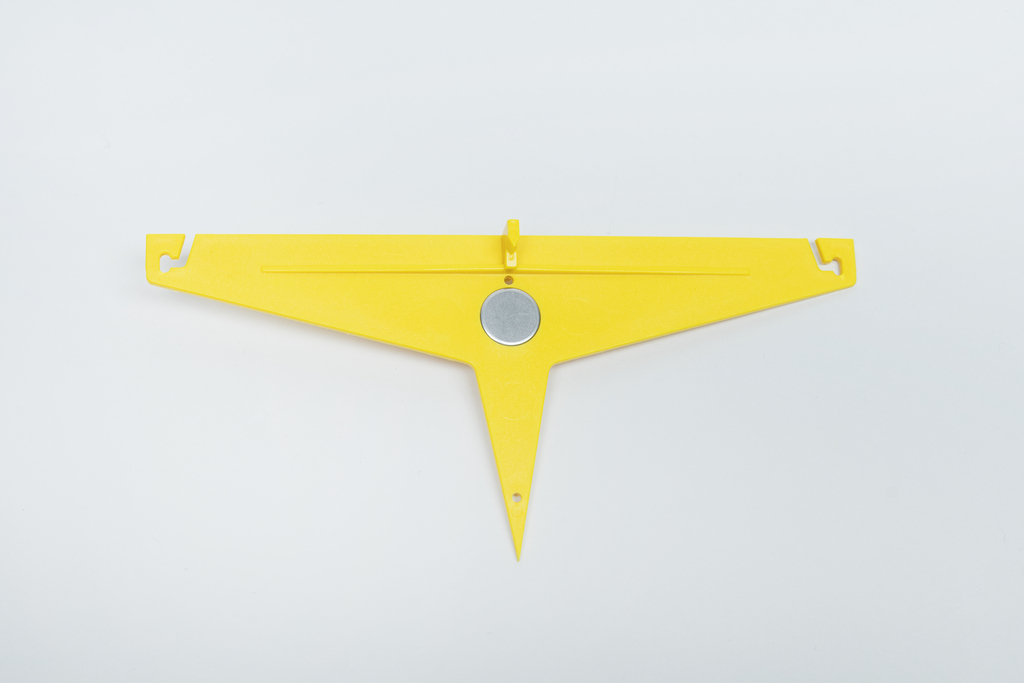 Das Bild zeigt ein gelbes, dreieckiges Messwerkzeug mit einer zentralen Magnetplatte und zwei seitlichen Haken. Es ist für den Einsatz im Bildungsbereich konzipiert, um Experimente und Messungen zu erleichtern.