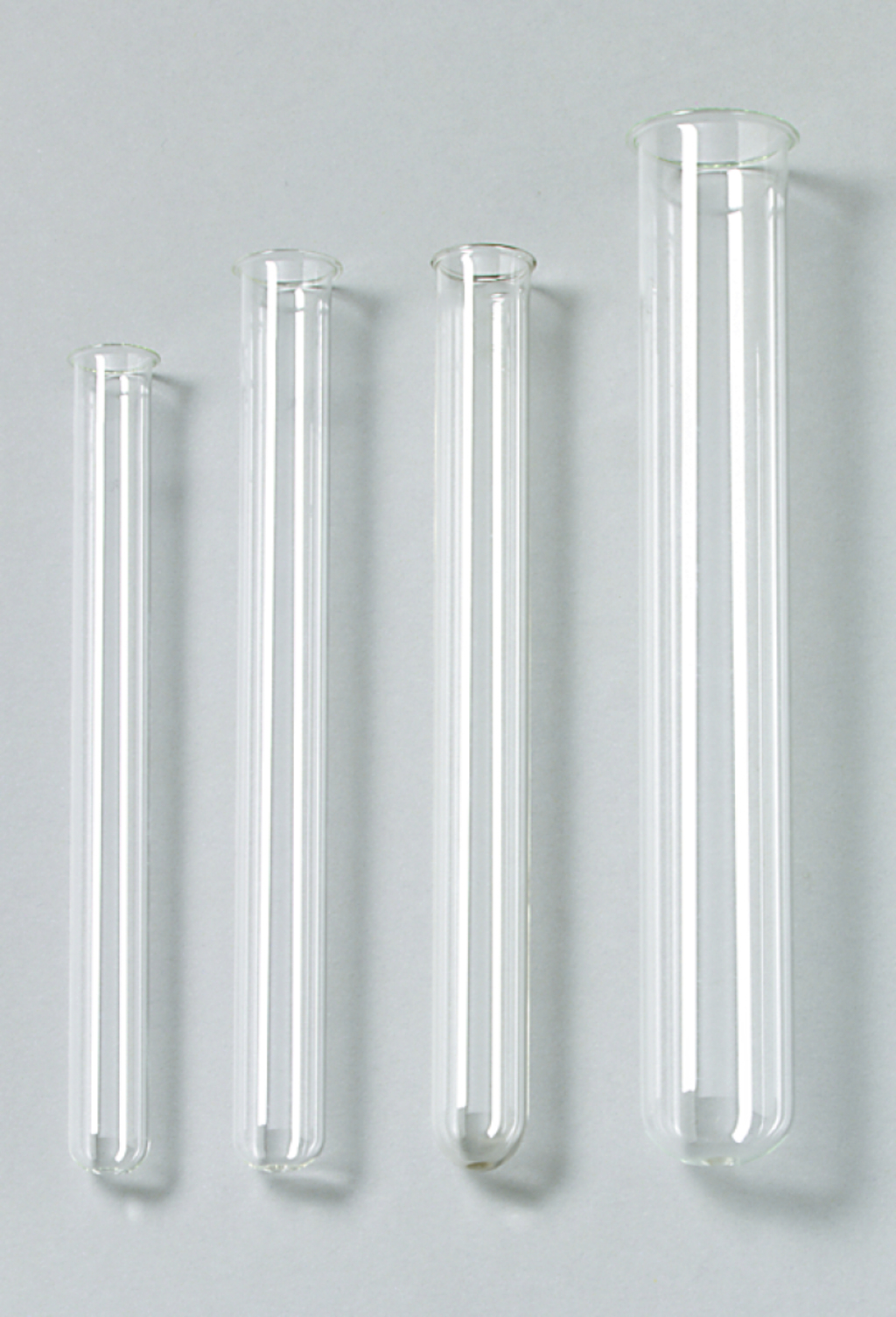 Das Bild zeigt vier klare, glasartige Reagenzgläser in unterschiedlichen Größen, die nebeneinander angeordnet sind. Sie sind für den Einsatz im Experimentierbedarf im Bildungswesen gedacht.