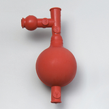 Das Bild zeigt ein rotes Gummigerät mit einer kugelförmigen Basis und mehreren Anschlüssen. Es wird wahrscheinlich als Teil von Experimentierbedarf im Bildungsbereich verwendet, um verschiedene chemische oder physikalische Prozesse zu demonstrieren.