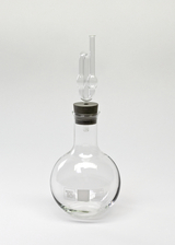 Das Bild zeigt ein chemisches Glasgerät, genauer gesagt einen Rundkolben mit einem eingebauten Stopfen und einem Glasrohr. Dieses Laborglasgerät wird häufig in Experimenten zur Durchführung von chemischen Reaktionen verwendet.