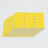 Das Bild zeigt mehrere Bögen mit gelben Haftetiketten, die auf hellgrauem Trägerpapier angeordnet sind. Diese Etiketten können für Kennzeichnungen oder Beschriftungen in Bildungsprojekten verwendet werden.