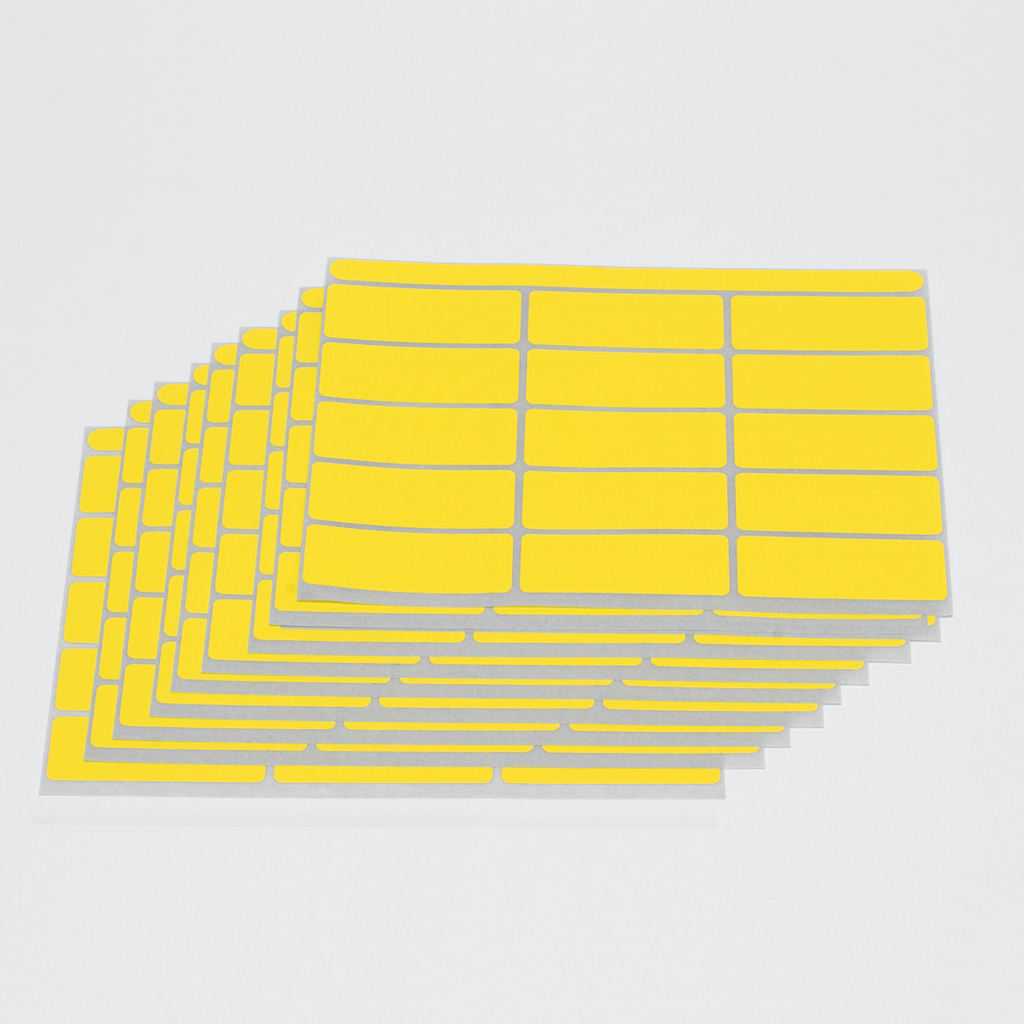 Das Bild zeigt mehrere Bögen mit gelben Haftetiketten, die auf hellgrauem Trägerpapier angeordnet sind. Diese Etiketten können für Kennzeichnungen oder Beschriftungen in Bildungsprojekten verwendet werden.