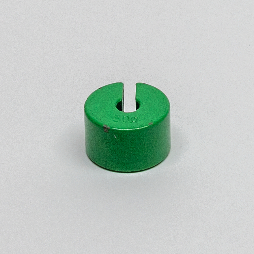 Das Bild zeigt einen grünen Gewichtszylinder mit einer Gewichtseinheit von 50 Gramm. Er hat eine eingeschnittene Form, die wahrscheinlich zur einfachen Handhabung und Befestigung in Versuchen dient.
