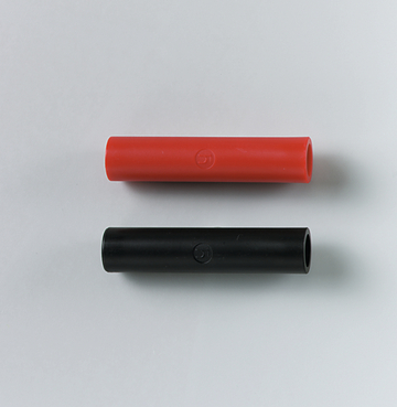 Das Bild zeigt zwei farbige Kappen in Rot und Schwarz, die aus flexiblem Material gefertigt sind. Diese Kappen sind vermutlich für elektrische Anschlussdrähte oder Versuchsaufbauten im Bildungsbereich gedacht.