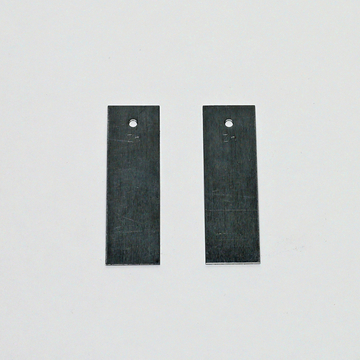 Das Bild zeigt zwei flache Metallstücke mit einer perforierten Stelle. Sie scheinen Teil eines Experimentierbedarfsets zu sein, möglicherweise für den schulischen Einsatz in naturwissenschaftlichen Fächern.