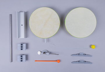 Das Bild zeigt eine Sammlung von Experimentiermaterialien, darunter zwei runde Platten, metallische und Kunststoffkomponenten sowie kleine Abstände und Halterungen. Diese Werkzeuge scheinen für praktische Experimente im Bildungsbereich konzipiert zu sein.