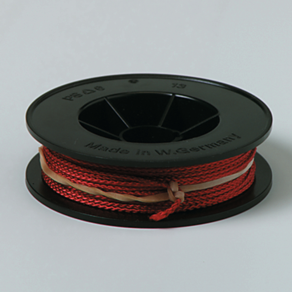 Das Bild zeigt eine Spule mit rot gefärbtem Draht, die auf einem schwarzen Kunststoffkörper gewickelt ist. Der Draht ist zur Verwendung in Experimenten im Bildungsbereich geeignet und stammt aus Westeuropa.