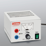 Das Bild zeigt ein elektrisches Experimentiergerät mit einem weißen Gehäuse, das über Anschlüsse für Plus- und Minuspol sowie einen Drehregler zur Spannungsanpassung verfügt. Eine Skala zeigt die Spannung in Volt an, und das Gerät hat einen Netzschalter.