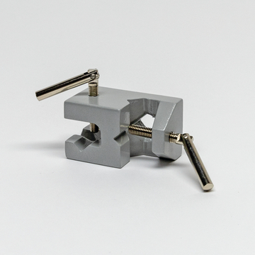 Das Bild zeigt einen grauen Experimentierklemmenhalter, der zur Befestigung von Materialien in wissenschaftlichen Experimenten verwendet wird. Er verfügt über Schrauben, um die Spannung einzustellen, und lässt sich somit leicht an verschiedene Objekte anpassen.