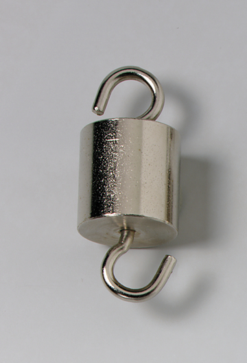 Das Bild zeigt einen metallischen Zylinder mit zwei Haken, der offenbar als Gewicht dient. Solche Gewichte werden häufig in experimentellen Anwendungen in Schulen verwendet, um physikalische Prinzipien zu demonstrieren.