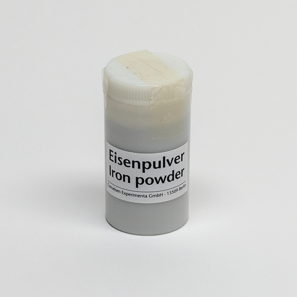 Das Bild zeigt ein transparentes Behältnis mit Eisenpulver, das für experimentelle Zwecke genutzt wird. Das Etikett weist auf den Inhalt hin und gibt die Marke sowie die Adresse des Herstellers an.