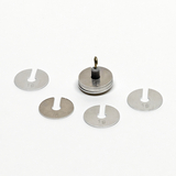 Das Bild zeigt eine Gruppe von Metallgewichten, die zum Experimentieren im Bildungsbereich verwendet werden können. Im Zentrum steht ein Gewicht mit einem Aufhängering, umgeben von weiteren Gewichten, die jeweils mit "1 g" beschriftet sind.