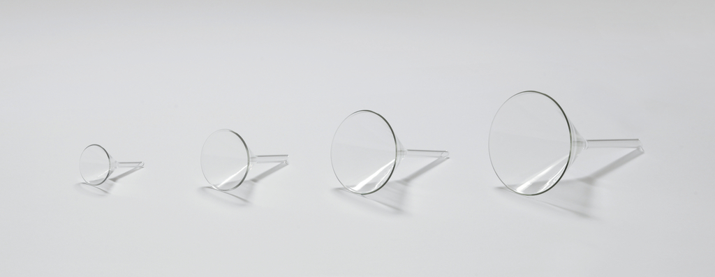 Das Bild zeigt eine Reihe von vier transparenten Trichtern in unterschiedlichen Größen, angeordnet von klein nach groß. Die Trichter bestehen aus klarem Material und haben einen schmalen Auslauf, ideal für die Verwendung in Experimenten oder in der Chemieausbildung.