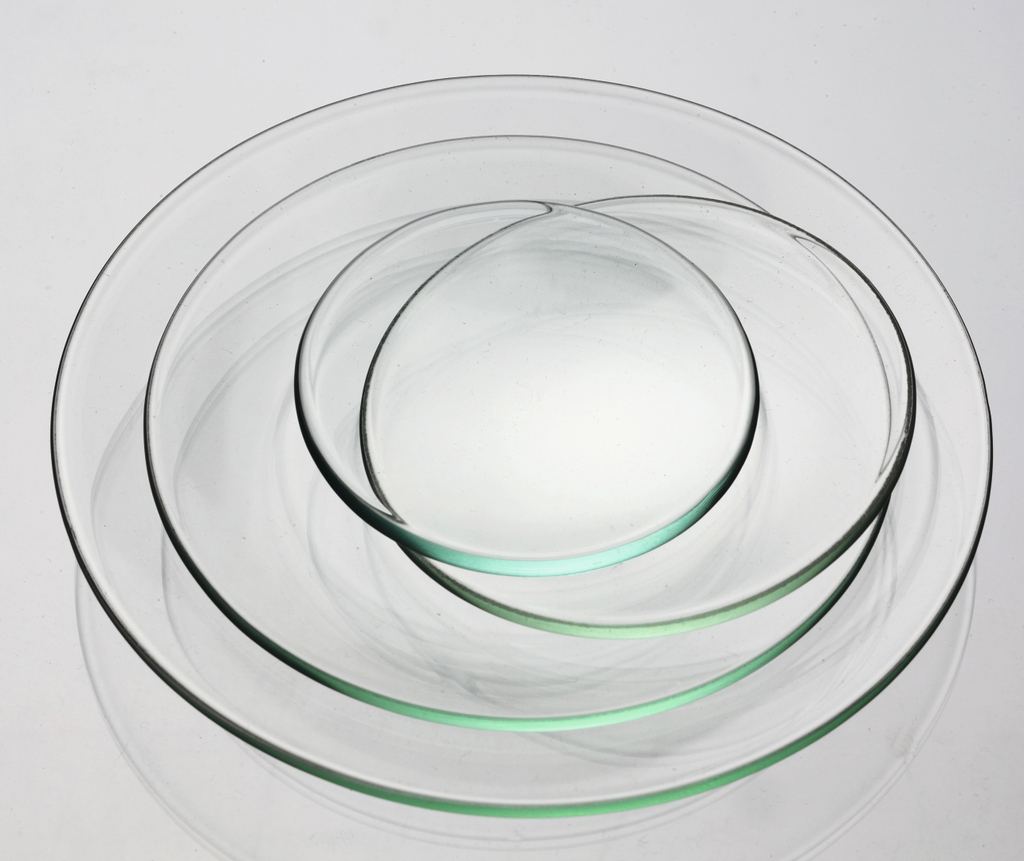 Das Bild zeigt eine Reihe von klaren, runden Glasplatten in verschiedenen Größen, die übereinander gestapelt sind. Diese Platten können für verschiedene Experimente und wissenschaftliche Anwendungen im Bildungswesen verwendet werden.