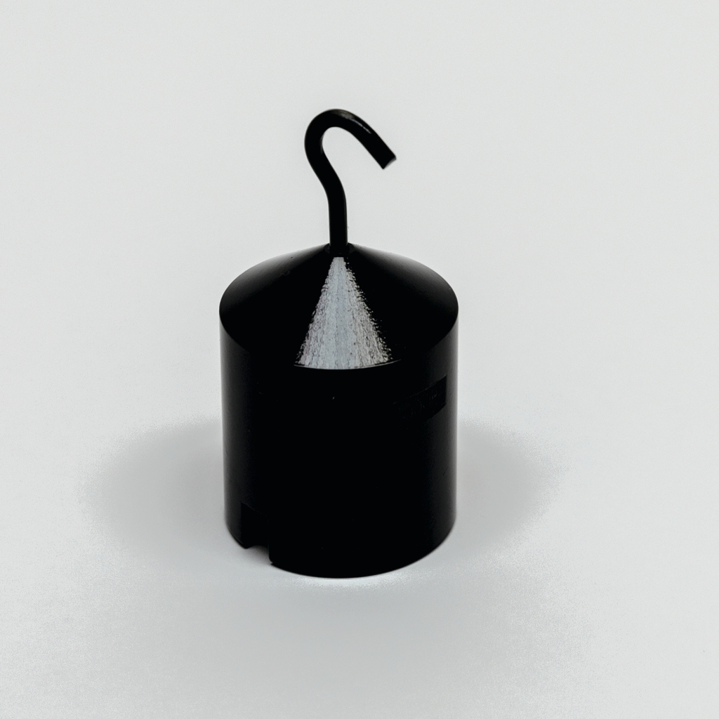 Das Bild zeigt ein schwarzes Experimentiergerät mit einem konischen Kopf und einem Haken, das vermutlich in naturwissenschaftlichen Schulen verwendet wird. Es scheint für die Durchführung von physikalischen Experimenten geeignet zu sein, möglicherweise zur Gewichts- oder Aufhängemessung.