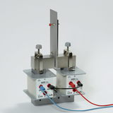 Das Bild zeigt ein Experimentiergerät, das aus zwei Modulen mit Messanschlüssen und einer zusammengebauten Metallstruktur besteht. Es wird wahrscheinlich zur Durchführung von elektrischen Experimenten oder Versuchen zur Messung von Widerstand und Stromstärke verwendet.