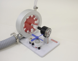 Das Bild zeigt ein Experimentiergerät zur Demonstration von Luftdruck und Mechanik. Es besteht aus einem roten Rad, einem Druckmesser und einem kleinen Motor, die zusammen eine lehrreiche Darstellung von physikalischen Prinzipien bieten.