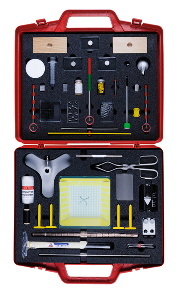 Das Bild zeigt eine rote Werkzeugkiste, die mit verschiedenen Experimentiermaterialien bestückt ist. In der Kiste befinden sich unter anderem Messgeräte, Chemikalien, Gläser und diverse Utensilien, die für naturwissenschaftliche Experimente genutzt werden können.