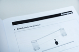 Eine Abbildung zeigt ein Versuchsaufbau zur Untersuchung der Belastbarkeit von Knochen. Zu sehen sind zwei Behälter, die an einem Stab hängen, wobei ein Gewicht in der Mitte platziert ist.