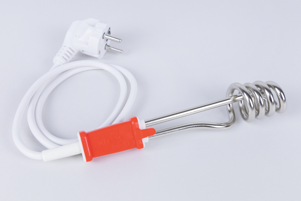 Ein elektrischer Heizstab mit einem weißen Kabel und einem roten Stecker ist abgebildet. Er wird häufig in Experimenten zur Erwärmung von Flüssigkeiten verwendet und ist ein nützliches Gerät für schulische Versuche im naturwissenschaftlichen Unterricht.