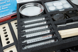 Ein Set für experimentelle Anwendungen im Bildungsbereich enthält mehrere Thermometer, eine Metallschüssel, Probenbehälter und Schutzbrillen. Die Anordnung ist sorgfältig auf einer Schaumstoffeinlage platziert, um die Materialien zu schützen und zu organisieren.