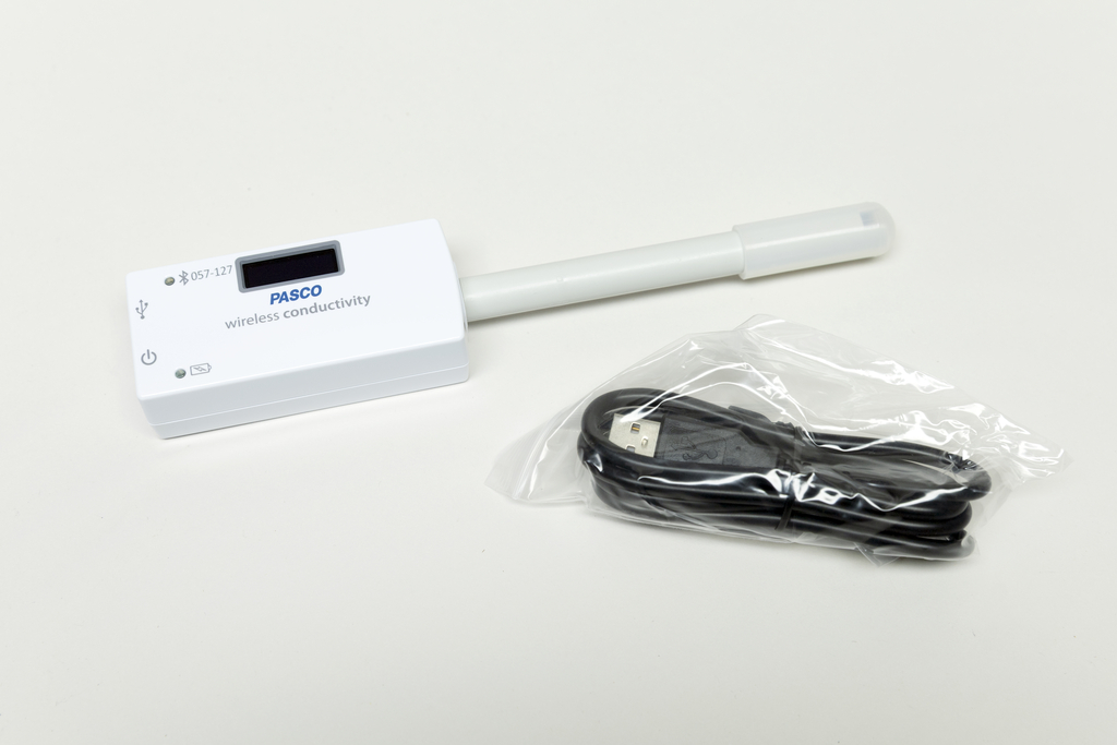 Ein kabelloses Messgerät für elektrische Leitfähigkeit ist abgebildet, das über ein digitales Display verfügt. Neben dem Gerät liegt ein USB-Kabel in einer Verpackung, um es mit Strom zu versorgen oder Daten zu übertragen.