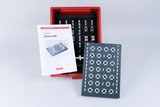 Ein Set für Elektronikexperimente ist in einer roten Box untergebracht, das verschiedene Bauteile für Schülerprojekte enthält. Dazu gehört ein Handbuch, das Anleitungen und Beispiele für die Durchführung von Experimenten bietet.