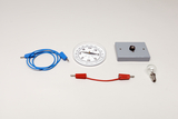 Ein Kompass, eine Glühbirne und ein grauer Schaltblock liegen auf weißem Grund. Zwei Anschlusskabel in Blau und Rot ergänzen das Set für physikalische Experimente.