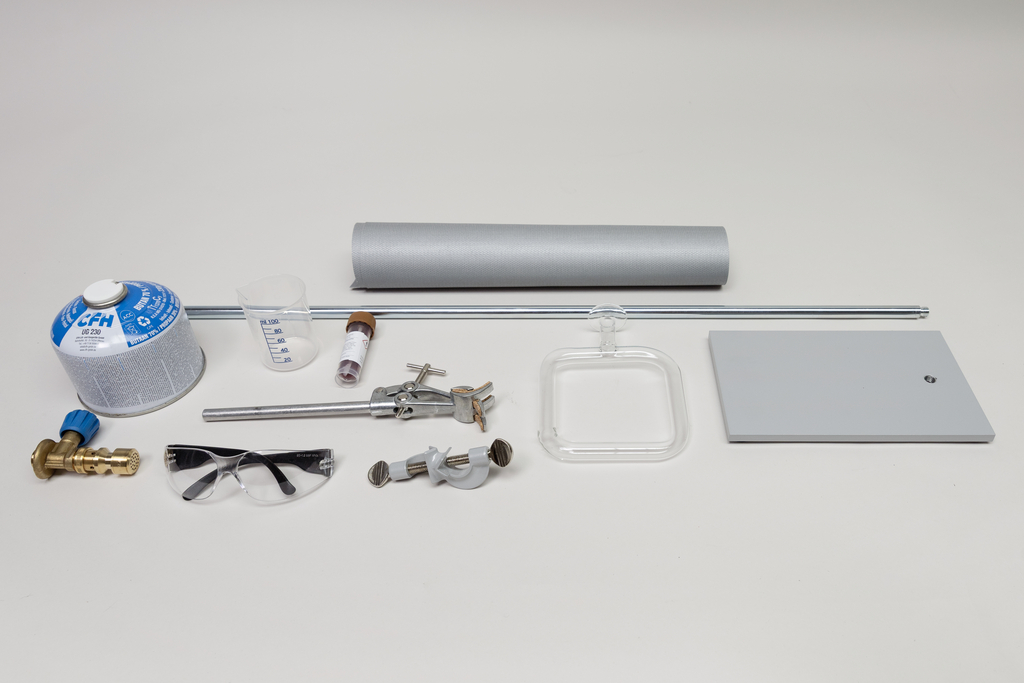 Verschiedene reflektierende Folien und Spiegeloberflächen sind auf einem hellen Untergrund angeordnet. Die Materialien dienen vermutlich zur Demonstration optischer Effekte in physikalischen Experimenten.