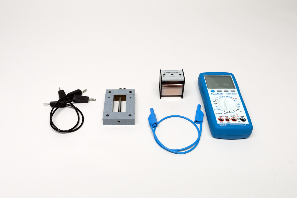Ein blaues Digitalmultimeter liegt neben verschiedenen Anschlusskabeln und Messleitungen. Ergänzt wird das Set durch zwei technische Messmodule auf weißem Hintergrund.