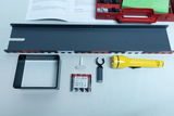 Ein Physik-Experimentierset mit Taschenlampe, Batterien und Zubehör liegt auf einem weißen Tisch. Ergänzt wird das Set durch eine Anleitung sowie eine rote Aufbewahrungsbox.