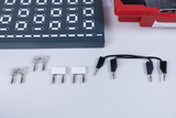 Ein elektronisches Experimentierset mit einer Steckplatine und verschiedenen Bauteilen. Zu sehen sind Widerstände, LEDs sowie Verbindungskabel auf weißem Hintergrund.