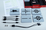 Ein Set aus grauen Modulen für Physikexperimente liegt zusammen mit schwarzen Verbindungskabeln und kleinen Glühbirnen auf einer weißen Fläche. Eine rote Aufbewahrungsbox sowie eine bebilderte Anleitung ergänzen das Lernmaterial.