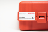 Eine rote Kunststoffbox enthält ein Cornelsen Schülerset für Experimente. Es handelt sich um das Set „Elektrik 2.0“ für Grundschaltungen auf Steckplatten.