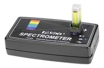 Ein schwarzes PASCO Spektrometer PS-2600 ist auf weißem Hintergrund abgebildet. In einer Halterung steckt eine Küvette mit einer gelbgrünen Flüssigkeit.