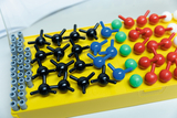 Ein gelbes Modellbau-Set zeigt verschiedene chemische Moleküle aus farbigen Kunststoffkugeln und Verbindungsstäben. Die Aufbauten repräsentieren unterschiedliche Molekülstrukturen für den Chemieunterricht.